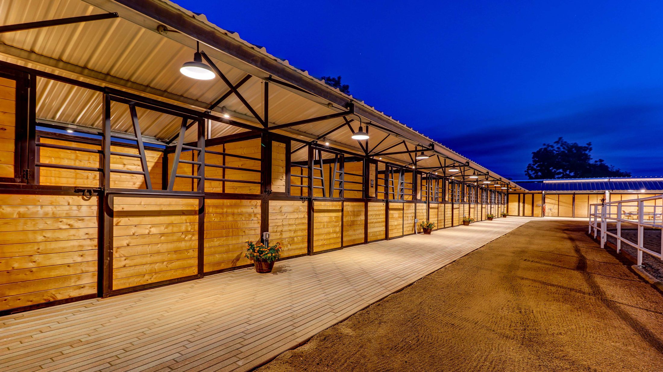 Barn aisle with stalls lit at dusk on an equestrian property