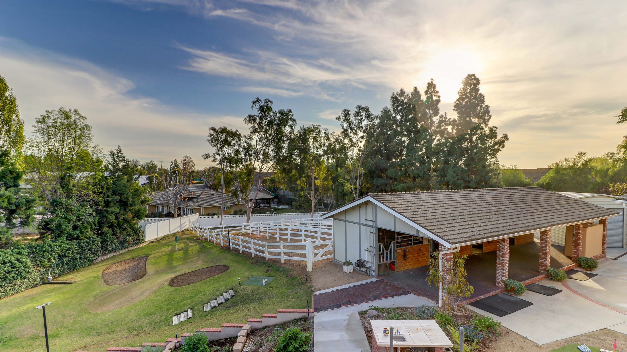 Ranch house and white fencing on a Yorba Linda horse property at golden hour